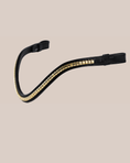Load image into Gallery viewer, Black leather bridle with gold accents on a beige background
